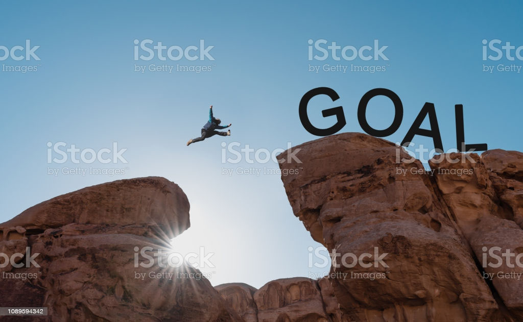 Cheesy stock photo of a man jumping over a ravine to a goal