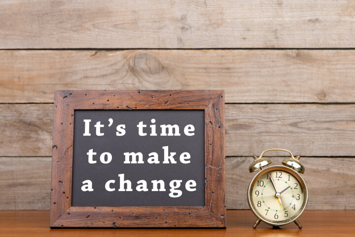 A picture of a clock next to a board saying, "It's time to make a change."